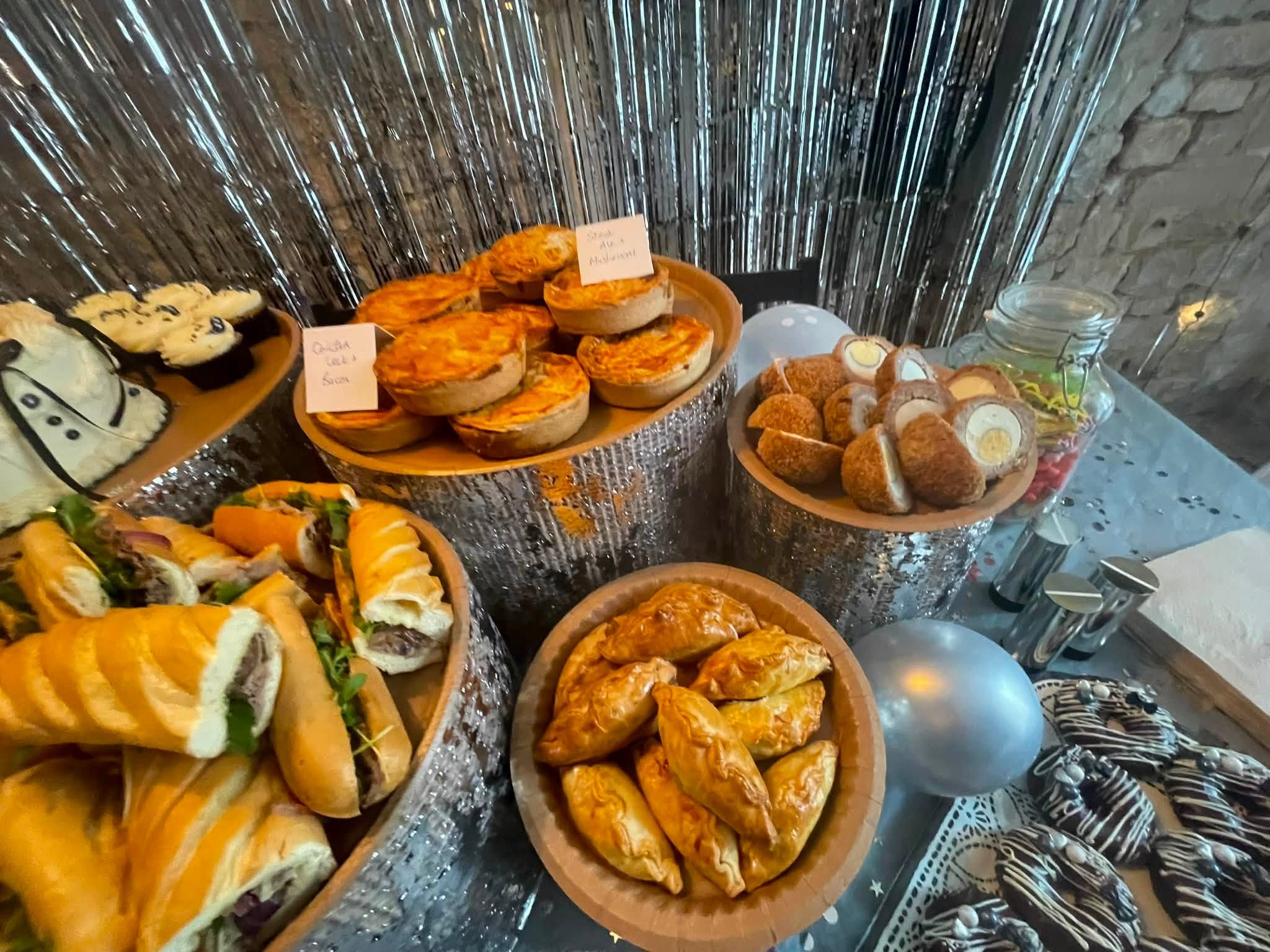 Close up of quiches, scotch eggs, filled baguettes and mini Cornish pasties on tiered stands