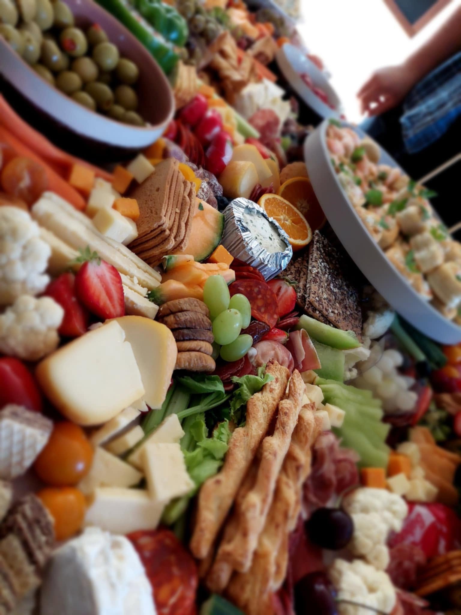 Close up of the grazing table with breadsticks, figs, grapes, strawberries, cauliflower, cured meats and a garlic dip