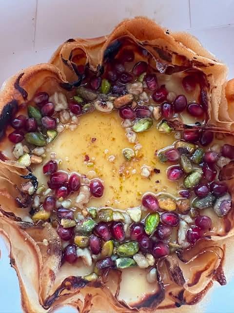 Baked feta in a crisp filo pastry case topped with pomegranate seeds, pistachios, walnuts and honey